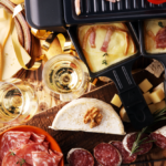 A hot raclette grill with its name-worthy raclette cheese is served with various types of meat, vegetables, and fresh bread.