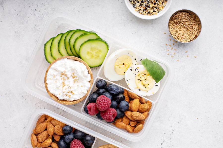 balanced snack with protein, fat and fiber displayed in a bento box style lunch box on a gray counter.