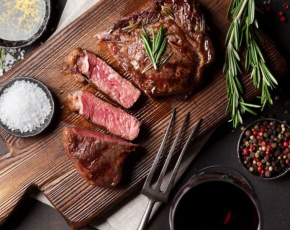 Steak cooked rare on a cutting board with seasoning around
