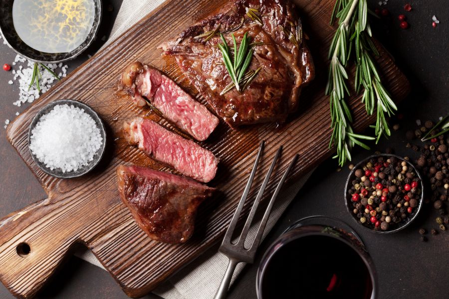 Steak cooked rare on a cutting board with seasoning around